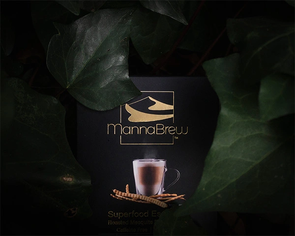 Mannabrew box inbetween large leaves in the woods