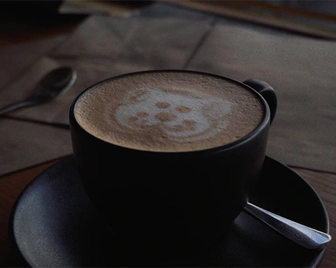 Closeup of a coffee cup with teddy bear foam art at Schoon Coffee Shop