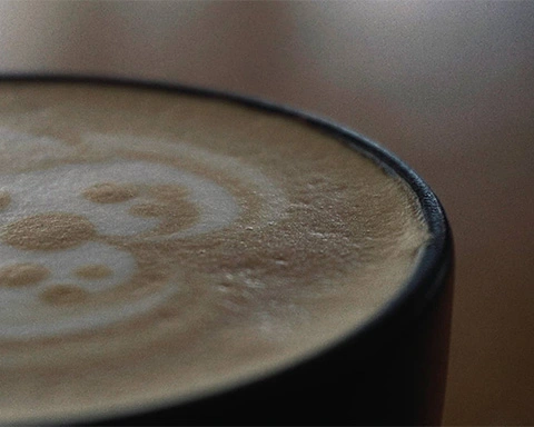 Exreme closeup of a coffee cup with a teddy bear foam art at Schoon Coffee Shop