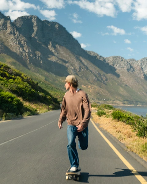 Man skateboarding on a beautiful coastal road in the morning sun